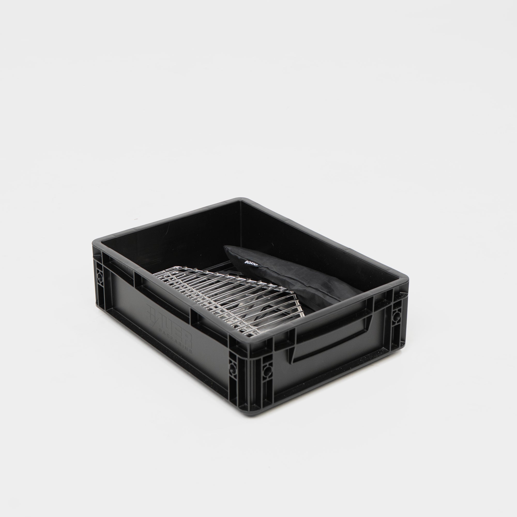 Schwarze Kunststoffbox mit einem Grillrost und einem schwarzen Deckel im Inneren.