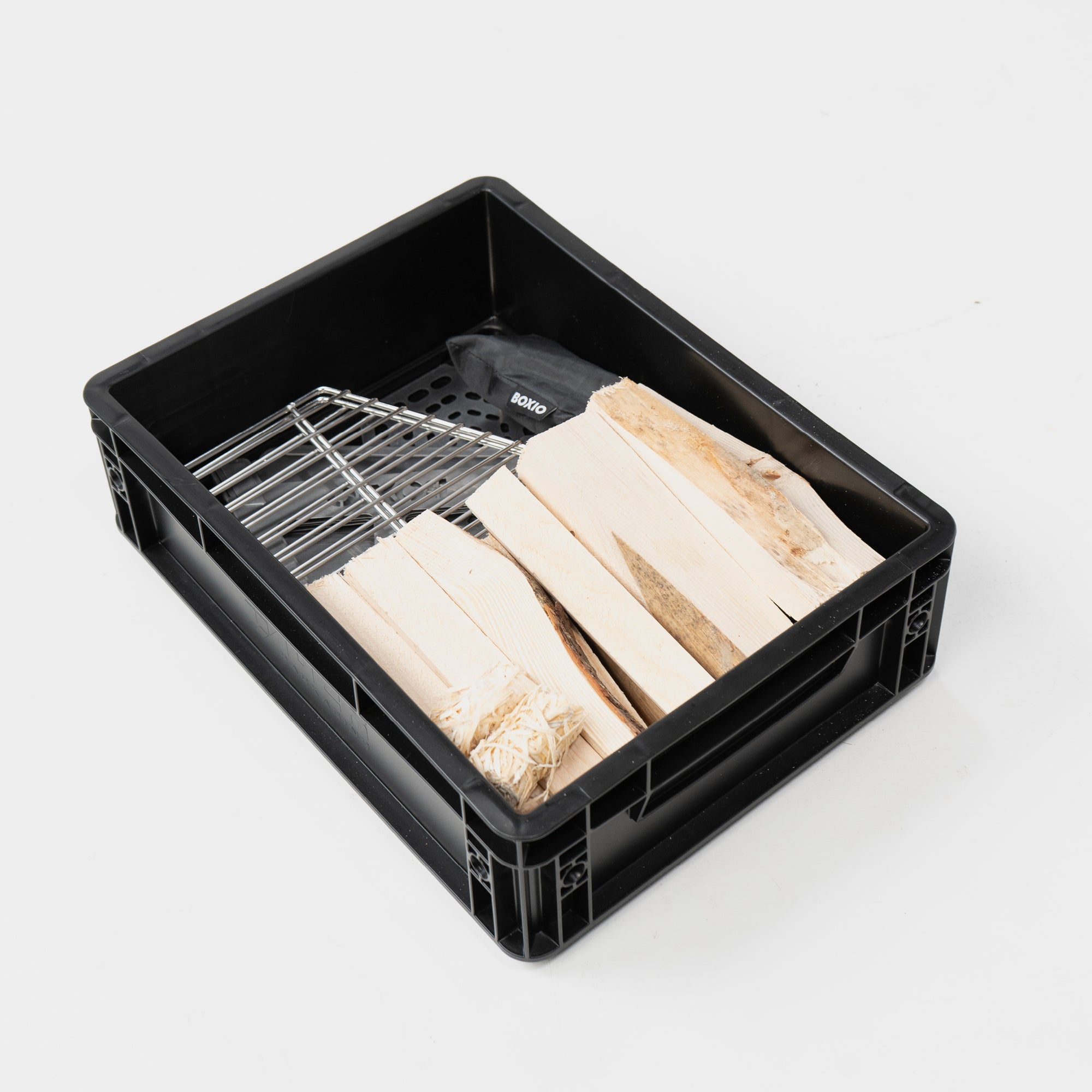 Schwarze Kiste mit Holzscheiten und einem Grillrost für das Grillen oder Räuchern.