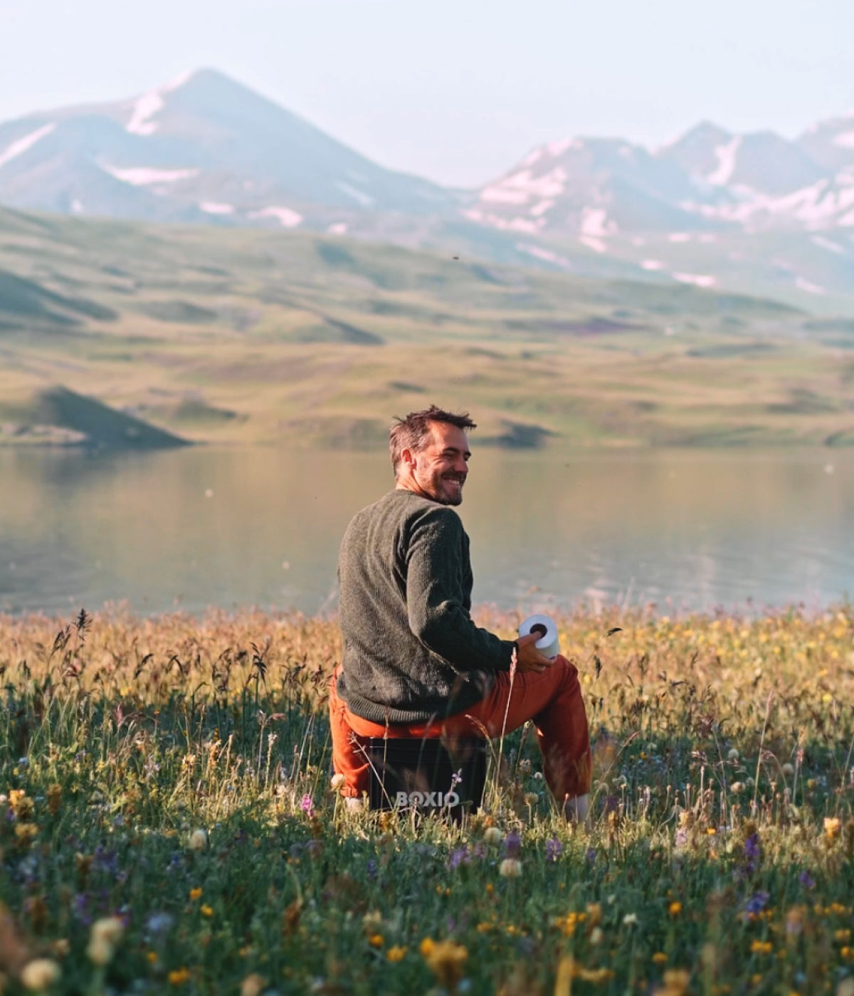 Mann sitzt in der Natur mit Bergpanorama auf einer Trenntoilette 