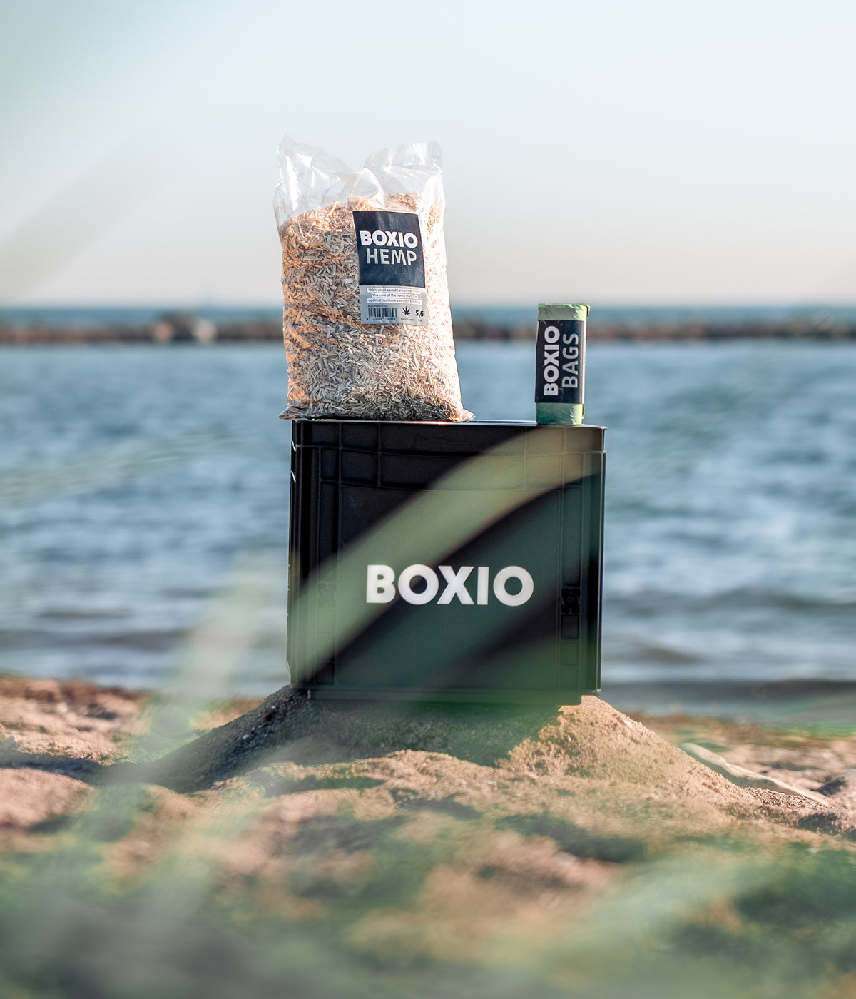 Boxio Toilet mit Wasser im Hintergrund und Streu und Tüten liegen auf der Box 